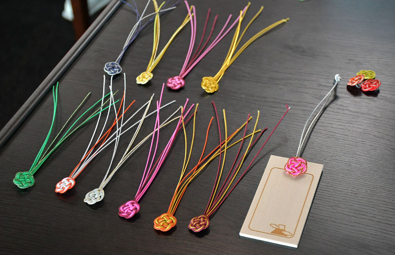 JALサンライトの社員が手編みした水引と日本風の絵が施されたスーツケースタグ